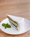 Japanese green tea matcha cake with white frosting and mint leaf served on white plate, on loght wooden background. Royalty Free Stock Photo