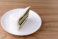 Japanese green tea matcha cake with white frosting and mint leaf served on white plate, on loght wooden background. Royalty Free Stock Photo