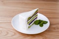 Japanese green tea matcha cake with white frosting and mint leaf served on white plate, on loght wooden background. Royalty Free Stock Photo