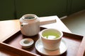 Japanese green tea in white cup and teapot on dark wooden serving tray in cute cafe Royalty Free Stock Photo