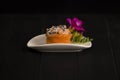 Japanese Gunkan sushi with fresh salmon and Tobico caviar served on white plate decorated with fresh flower