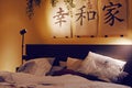 Japanese interior. Painting with hieroglyphs. Bed and pictures above it. Evening room background. Bedroom, pillows on the bed