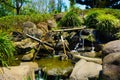 A japanese or japan graden style with water bamboo pipe line with green grass and water flowing on small pond with rock and stone