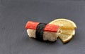 Kani nigiri sushi served with lemon on black slate stone.