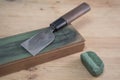 Japanese leather craft knife on a leather knife strop with green polishing compound on a wooden surface Royalty Free Stock Photo