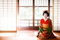 Japanese Maiko, Geisha in red costume sit in Tatami floor room w