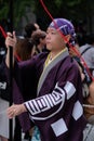 Handsome Japanese male dancer in colorful kimono and headband carrying banner