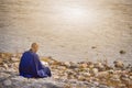 Japanese Male Monk in Blue Robe Reading Book on River Bank