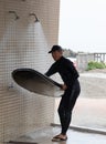 Japanese man in black wetsuit cleaning up his surfboard Royalty Free Stock Photo