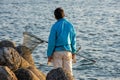 Japanese man with fishing net rod fishing at seashore in Osaka Bay, Japan