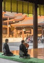 Japanese man sitting playing on a traditional tsuzumi drum in Shinto Meiji-jingu shrine