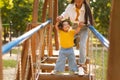 Japanese Mother Helping Little Baby Walk Swinging Bridge On Playground Royalty Free Stock Photo