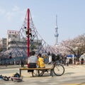 Japanese mother and son at a playground with cherry blossom and Tokyo Skytree in the background