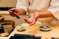 Japanese Omakase making Trout Sushi and adding Shoyu sauce on fish neatly by brush in his palm. Royalty Free Stock Photo