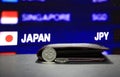 Japanese one hundred Yen coins on obverse JPY and one coin laying on black floor with black wallet and digital board of currency Royalty Free Stock Photo