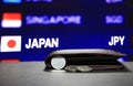 Japanese one Yen coins on obverse JPY and pile of other Japanese coins on black floor with black wallet and digital board. Royalty Free Stock Photo