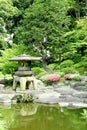 Japanese outdoor stone lantern, flower plants in zen garden Royalty Free Stock Photo