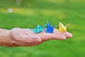 Japanese paper crane on male hand as symbol of happiness on green background