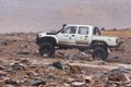 Japanese pickup truck Toyota Hilux driving on rocky mountain road on background volcanic stone landscape. Off-road trip