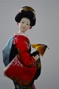 Japanese porcelain doll in japanese kimono costume, with red decorated handbag, golden punka fan n left hand Royalty Free Stock Photo