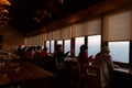 Japanese restaurant with tourists on window side table to sea view of sunset over sea