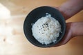 Japanese rice with black sesami on top in the black bowl and chopsticks on the wood table