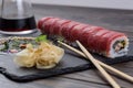 Japanese roll with tuna. Roll with ginger and soy sauce on a black slate