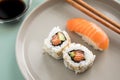 Japanese salmon Nigiri and inside out California Sushi with avocado, soy sauce and wooden chopsticks on porcelain plate