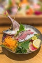 Japanese seafood sashimi cuisine of Ayu raw fish pierced on a skewer served in a metal plate.