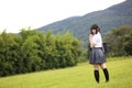 Japanese school with umbrella on rain in countryside with grass