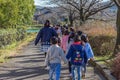 Japanese schoolchildren in colourful clothes walking with their teacher.