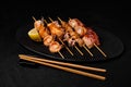 Japanese Seafood Skewers. Black tiger shrimp, scallop and salmon fillet, octopus served with sauce. Yakitori isolated on black Royalty Free Stock Photo