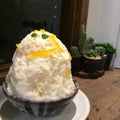 Japanese shaved ice, Yusu orange yogurt Kakigori top with little mint leaf on the wood table with blur bokeh cactus background