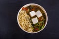 Japanese soup with tofu, noodles, vegetables and herbs, on a black background. Copy spaes