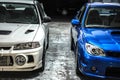 Front view of blue Subaru Impreza and white Mitsubishi Lancer Evo 4