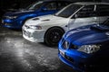 Front view of two blue Subaru Impreza and white Mitsubishi Lancer Evo 4