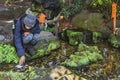 Japanese squatting by a pond making a shinto purification ritual at Kawagoe Hikawa shrine in winter. Royalty Free Stock Photo