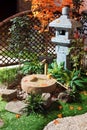 Japanese stone lantern in the garden with cho-zu fountain and maple. Traditional asian fountain in the park.