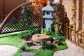 Japanese stone lantern in the garden with fountain and maple. Traditional asian fountain in the park.