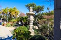 A Japanese stone tower in a garden surrounded by lush green plants and trees near a walking path Royalty Free Stock Photo