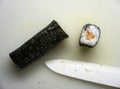 Japanese style rice nori roll with salmon near ceramic blade knife on cutting board top view Royalty Free Stock Photo