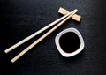 Japanese sushi chopsticks over soy sauce bowl, rice on black bac Royalty Free Stock Photo