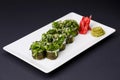 Japanese sushi with rice and fish and seaweed salad on top. Served on a white plate over black background Royalty Free Stock Photo