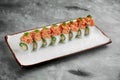 Japanese sushi roll with crab, avocado and spicy tuna in a white plate on a gray background Royalty Free Stock Photo