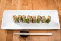 Japanese sushi roll green dragon with eel and avocado with ginger on a white plate. isolated. close up Royalty Free Stock Photo