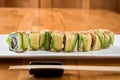 Japanese sushi roll green dragon with eel and avocado with ginger, lime, on a white plate Royalty Free Stock Photo