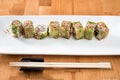 Japanese sushi roll green dragon with eel and avocado with ginger on a white plate. isolated. close up Royalty Free Stock Photo