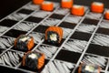 Playing chess with black and white Philadelphia sushi black roll pieces on chalkboard background. Royalty Free Stock Photo