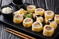 Japanese sushi set roll with rice, omelette, cheese, salmon and avocado served with sauces, wasabi and ginger on a plate.