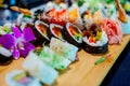 Sushi rolls well served on wooden plank.